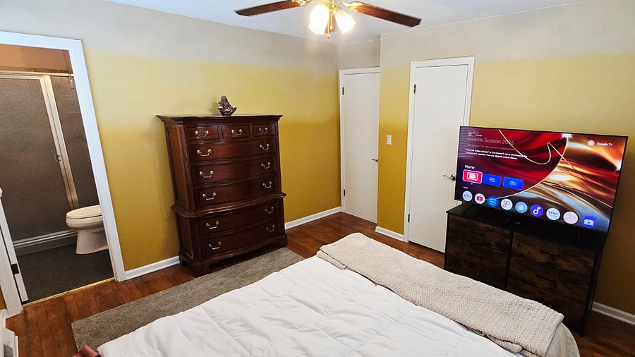 Master bedroom with two dressers and 55" Smart TV.