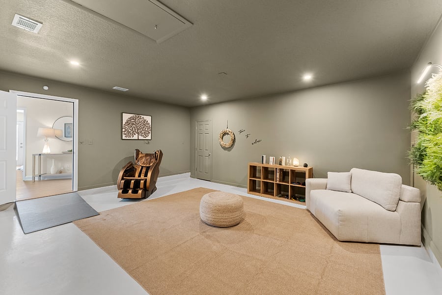 A second view of your peaceful wellness spacefeaturing a massage chair, soft lounge seating, greenery, salt lamp, yoga gear, and curated books. Thoughtfully designed to help you unwind, de-stress, and restore both body and mind.