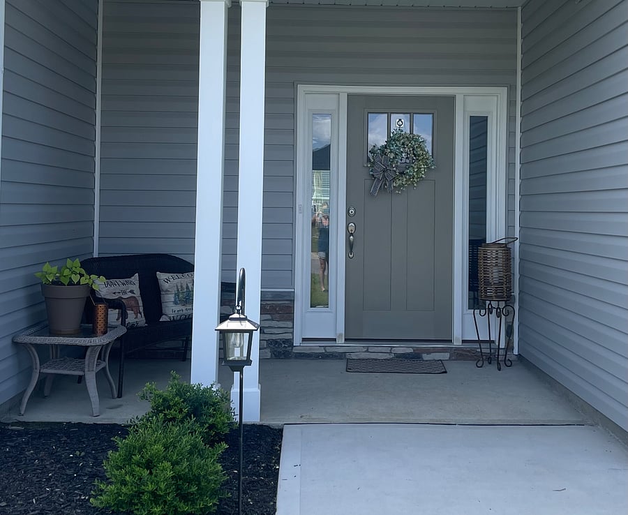 Front door with covered porch area and seating.