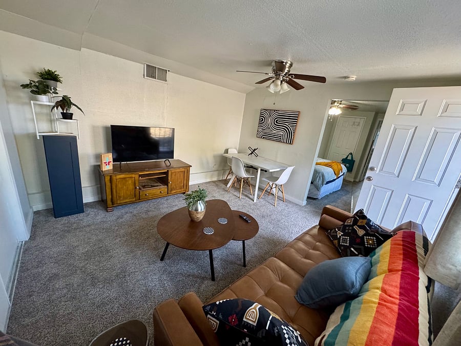 Separate living room with couch, smart TV, and table.