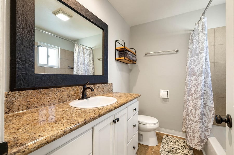 Bathroom with full size mirror, facet, toilet and rain shower over tub