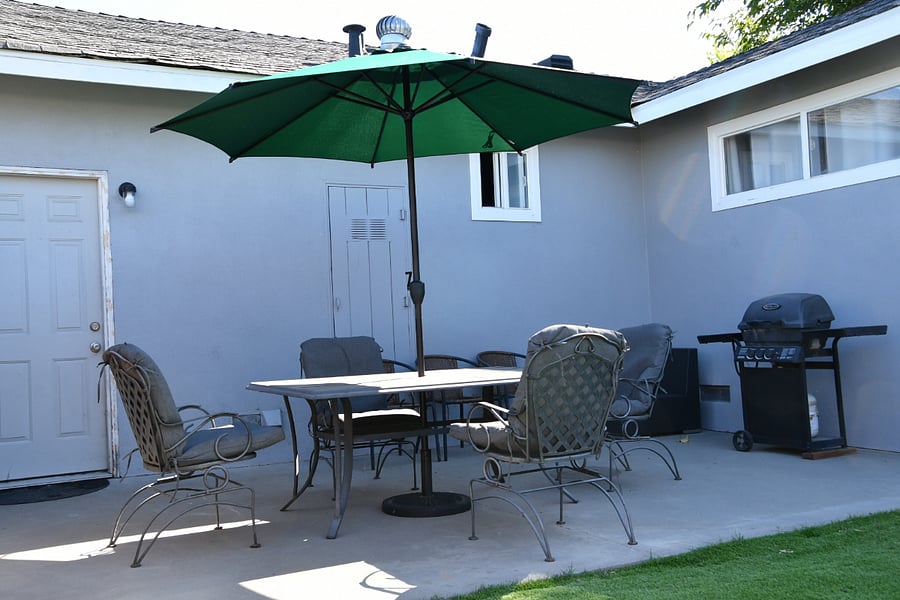 Private backyard with half concrete, half artificial grass. One Outdoor 4 chair table with Umbrella shade. Extra chairs. Propane BBQ.