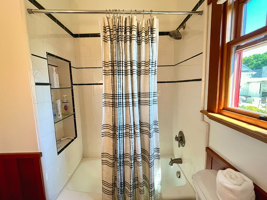 Tiled shower/bathtub has built-in storage for toiletries, soap and shampoo.