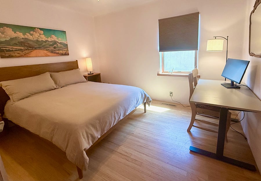 guest bedroom featuring a queen size bed, built in closet and drawers, and remote workspace with adjustable stand up desk.