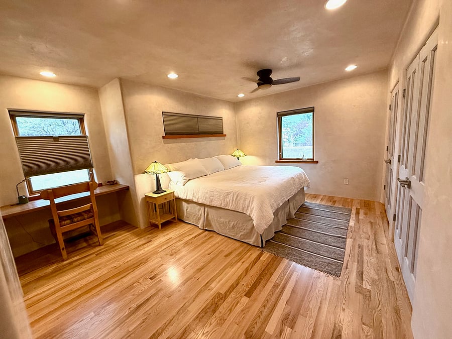 primary bedroom with comfortable king size bed, ample storage, darkening shades, and built in remote work area.