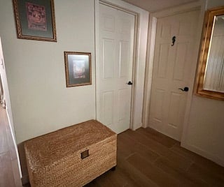 When you look to your left, you see the view of the entrance. The door to the left opens to the bedroom, and the right door opens to the bathroom. 

The chest is conveniently placed to put your bags on. It stores a yoga mat, blocks, light weights, and other workout gear. There is plenty of space to roll out the mat in front of the mirror. 