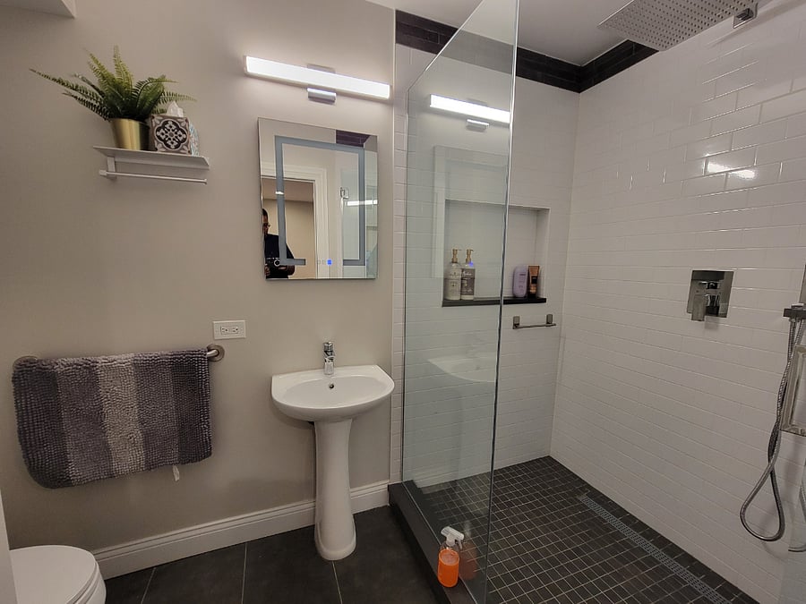 Spacious shower with overhead and handheld options.