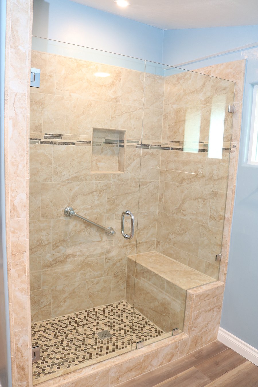 Large granite and tile shower with bench seating for comfort and convenience