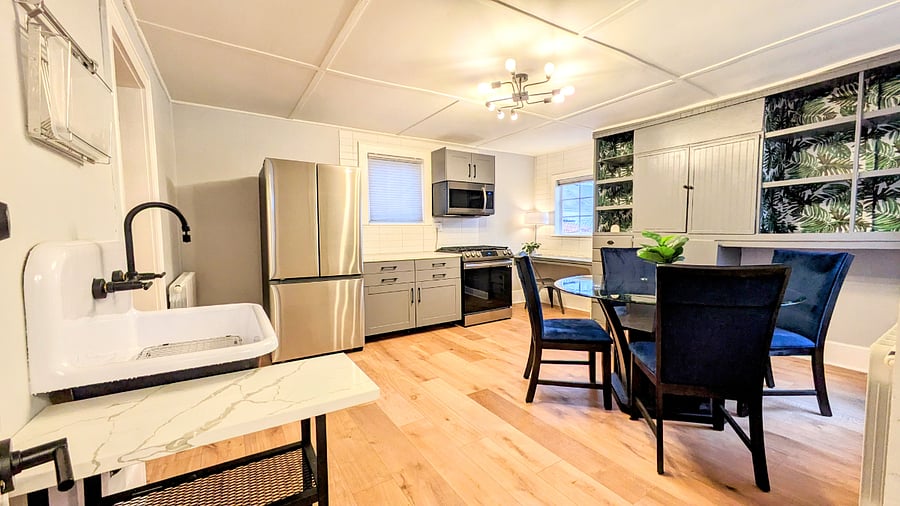The lower unit kitchen has original builtins, the original farmhouse sink and new quartz counters, new stainless appliances, and eat in dining room with work station