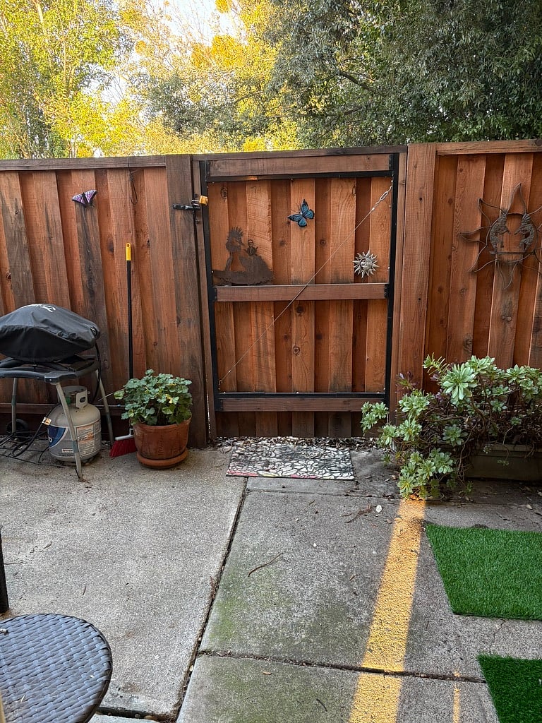 A portion of the view into the back patio. There is a loveseat and cushions with a small outdoor table as well. 