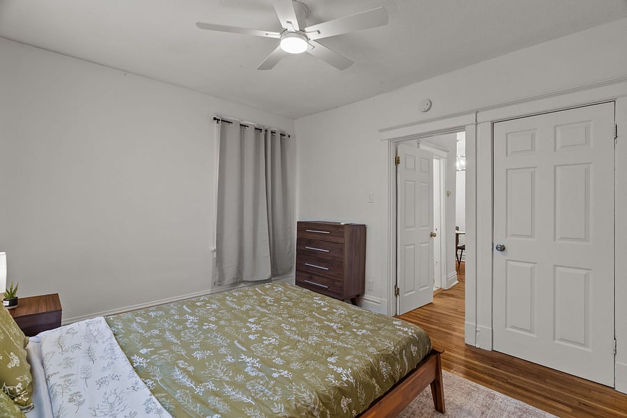 REAR BEDROOM. Real wood queen bed with extremely comfortable mattress above a nice rug. Black out curtains. Wall art, and chest of drawers are shown in other pictures. Also not shown is a single seating chair in corner for reading and lounging.