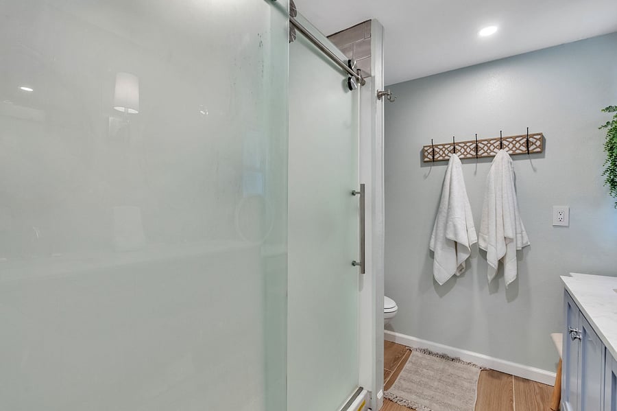 Master bathroom showing full sized shower with sliding glass door. Commode behind shower wall. 