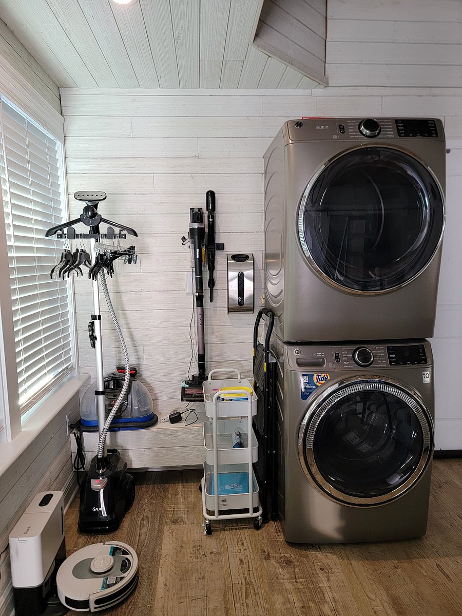 Laundry with clothes steamer, cordless vacuum, robot vacuum, and steam cleaner.