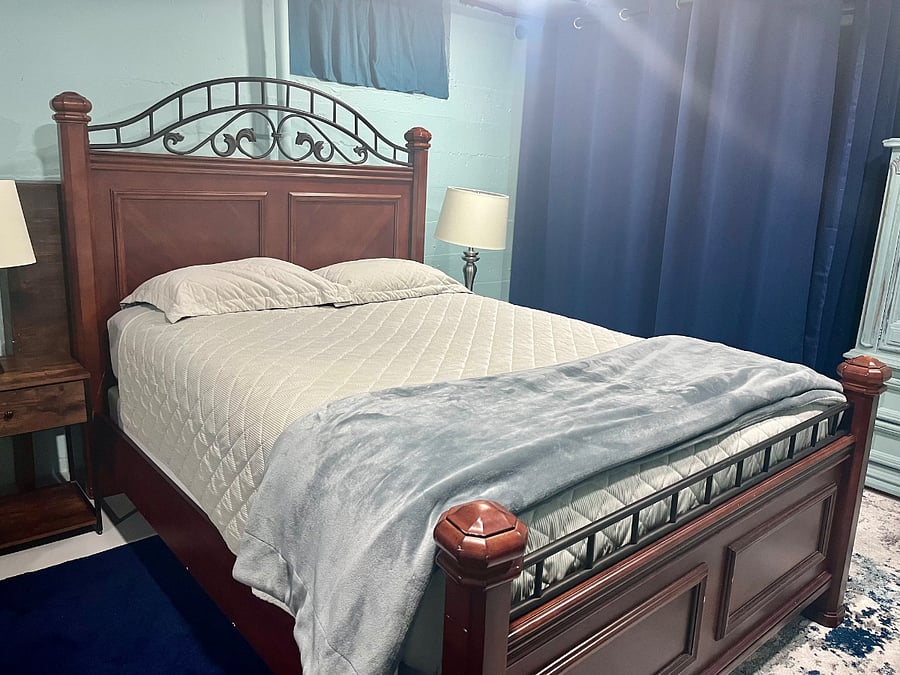 Queen size bed with mattress topper for a comfortable night's sleep! There are nightstands on both sides of the bed with electrical plugs for easy charging at night.