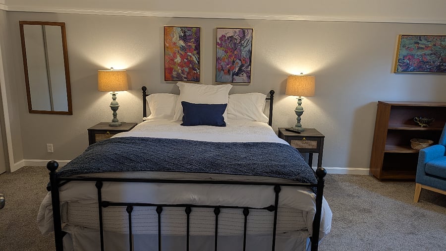 Queen size bed with side tables and lamps. Comfortable bedding with a duvet.