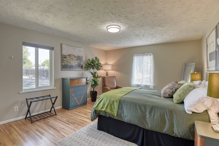 Large bedroom with queen bed, abundant lighting and blackout window shades.