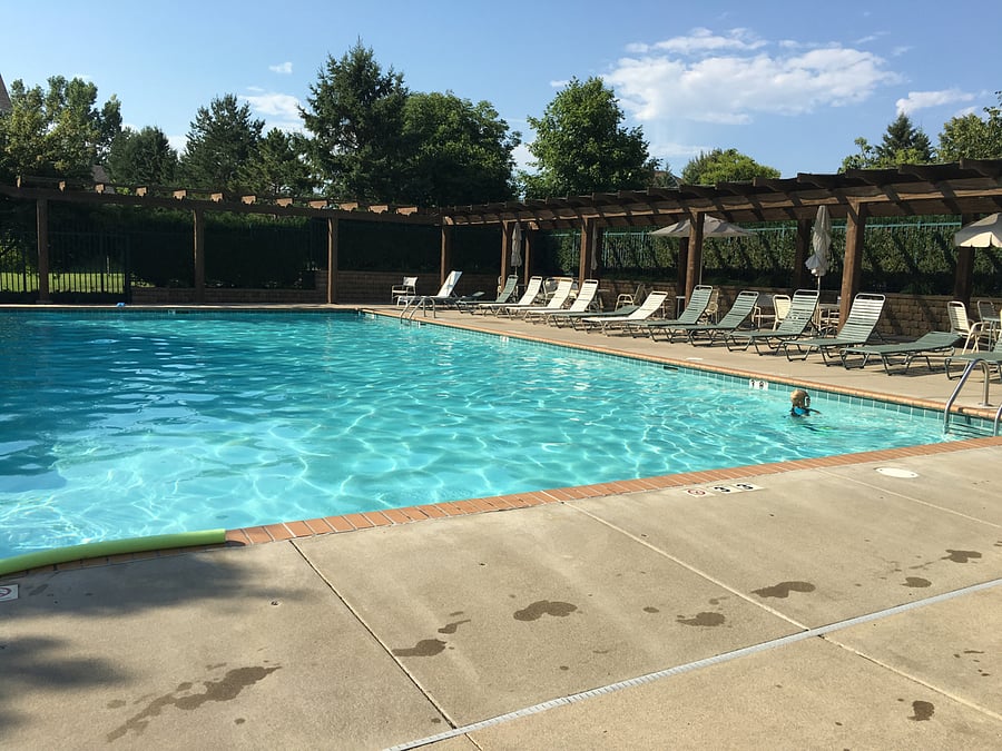 Community Pool with Tables, Umbrellas, Sun Chairs, and Bathrooms.