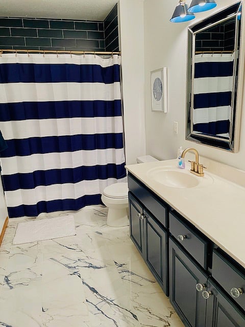 Shared bathroom with double vanity and rain shower head.