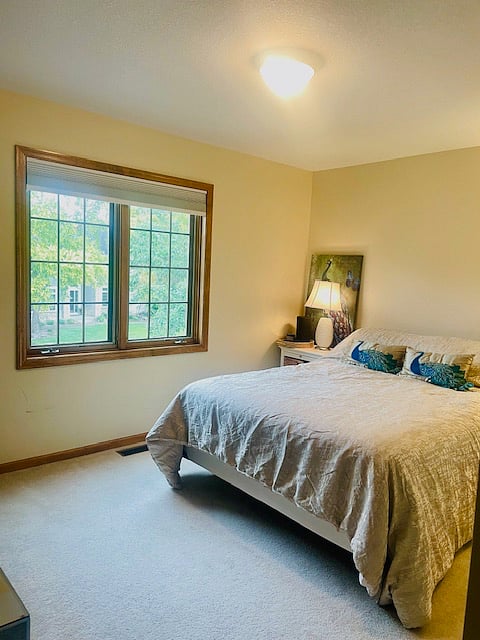 Large bedroom, lots of natural light with tv, desk, small refrigerator/freezer, and walk-in closet.