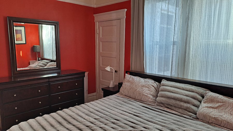 Primary Bedroom. king size bed with storage. two dressers. faux fire place. small closet.