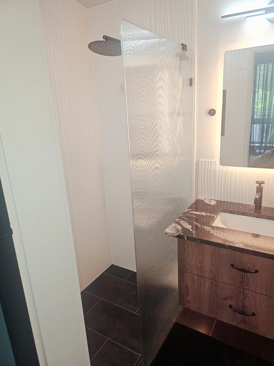 Spacious walk-in shower featuring a luxurious rainfall showerhead.