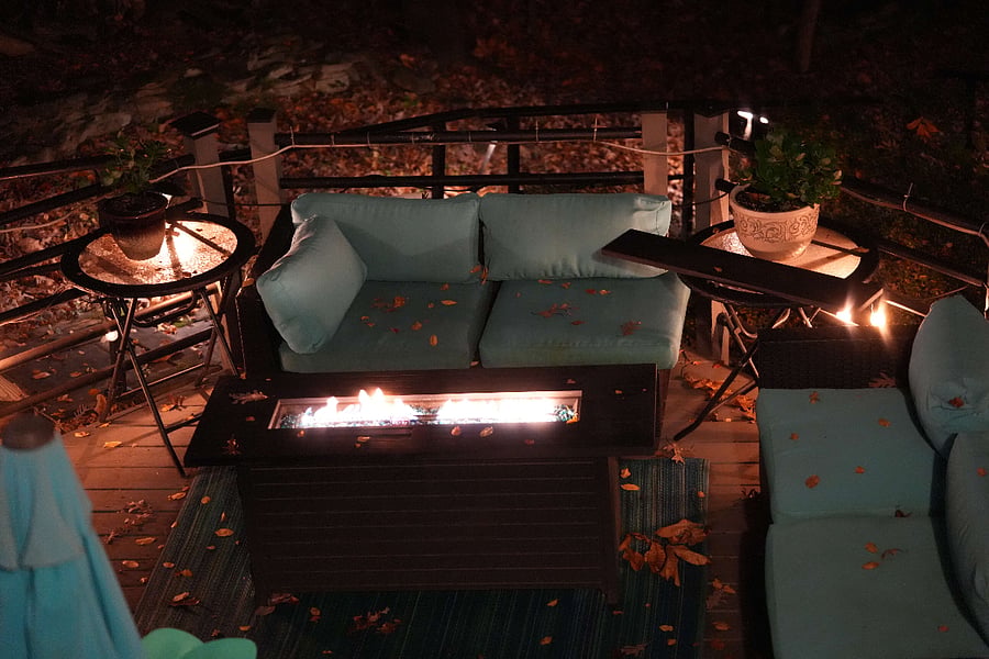 a view of the deck from the hot tub with the uplighting on trees and the lights leading down to the lake