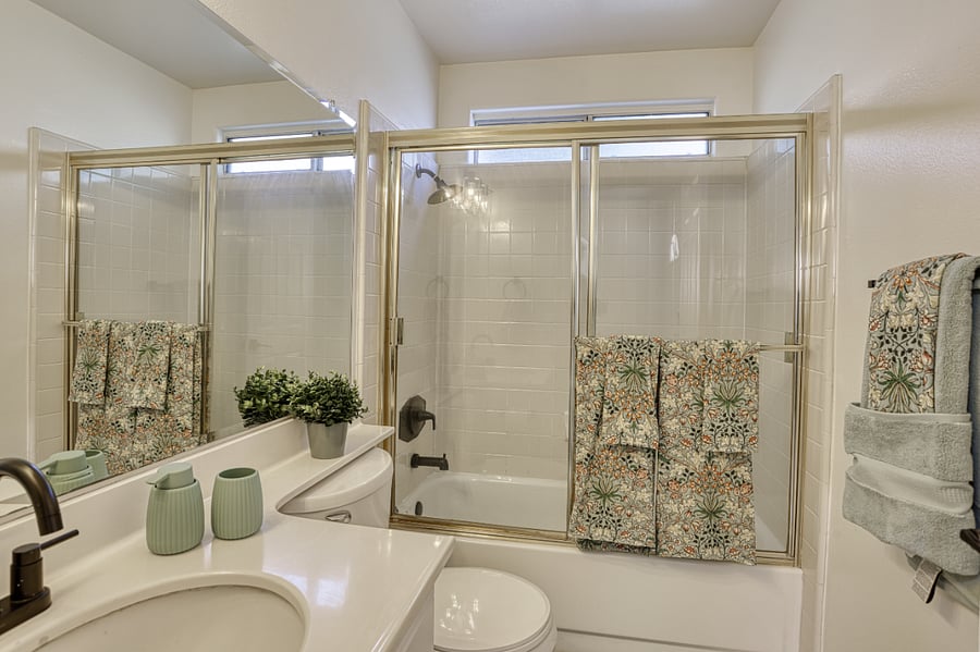 Indulge in a peaceful morning routine in this bright and meticulously maintained bathroom. The clean white tiling and soft sage accents create a calming, spa-like environment that helps you start your day on a high note.