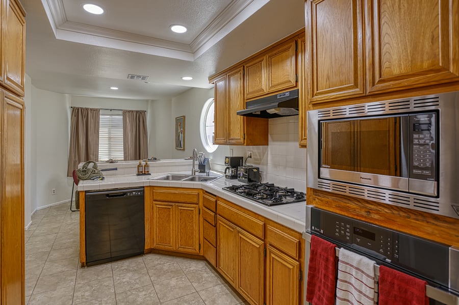 Prepare your favorite meals with ease in this bright and spacious kitchen, featuring a functional layout and all the modern conveniences of home. The warm wood cabinetry and clean white tiling create a classic, inviting space for any culinary task.