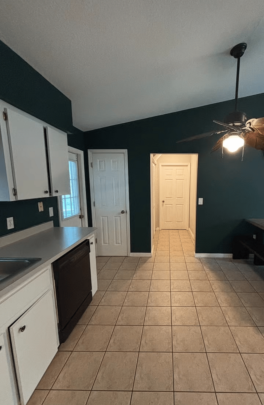 Kitchen View to Laundry Room Door, and Side Exit. Also Door to Spare Bedroom 1 is on the Right in the Hall