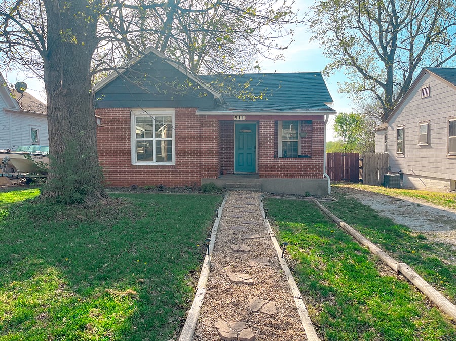 A cute little brick house with a bright, blue front door. Our pathway is lit by solar lights (if they get enough sun beneath the big, old tree!) There is free parking on the gravel drive on the right side of the property. 