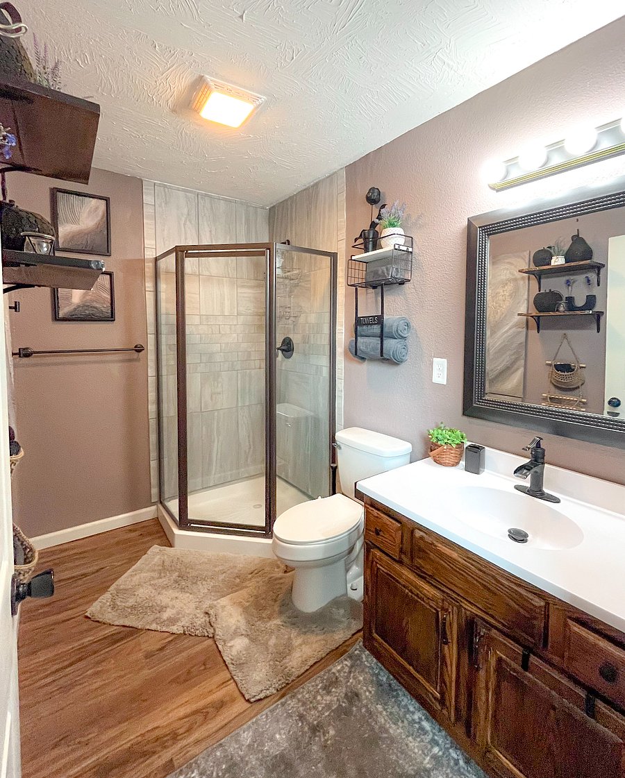 Indulge in a refreshing shower beneath the relaxing rainfall showerhead in our newly remodeled bathroom, complete with custom tilework, cozy bath mats, and comfortable cotton towels. 