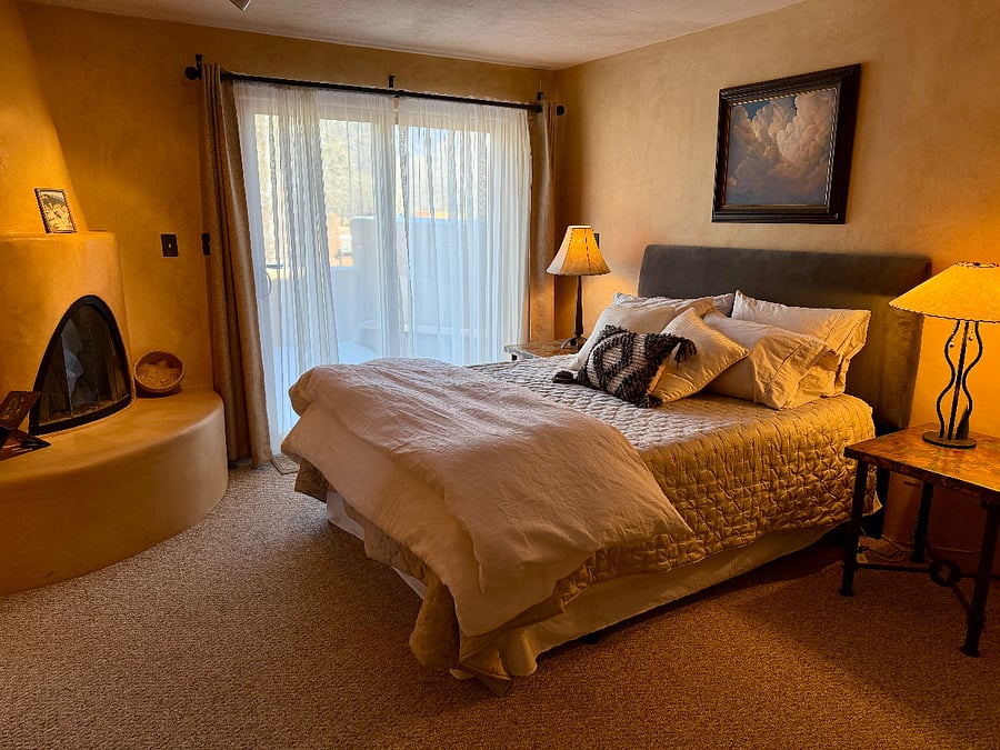 Primary bedroom, which features its own gas fireplace, as well as a spacious deck, with a view of Taos Mountain.