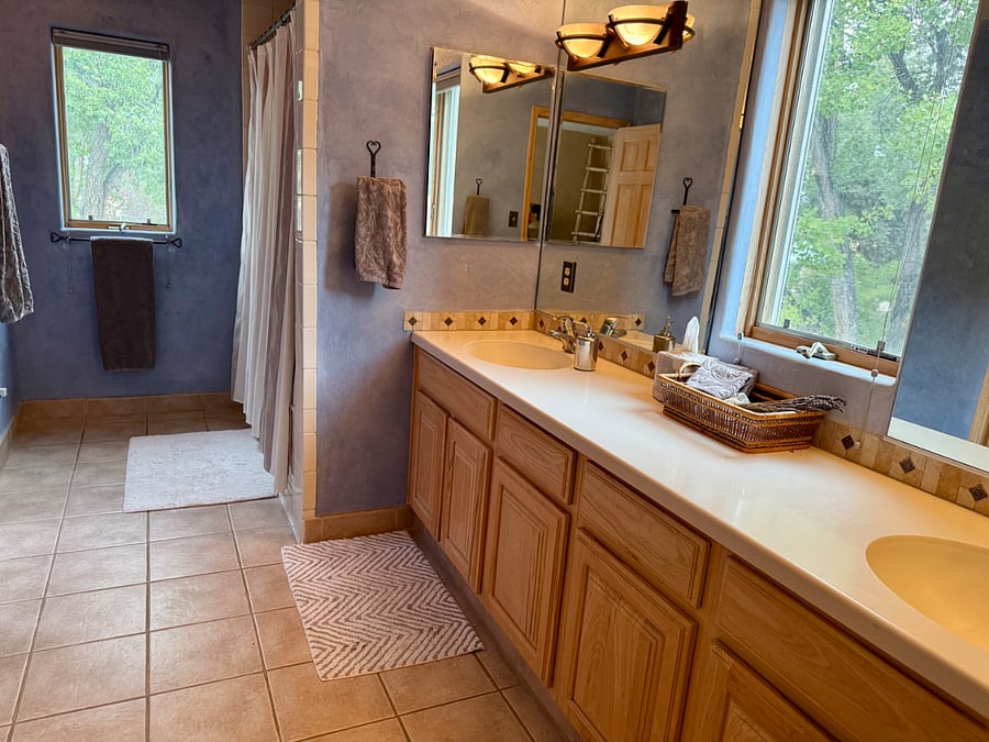 This spacious bathroom, with double sinks, a large tub/shower, a private toilet room, and a walk-in closet, adjoins the main bedroom.