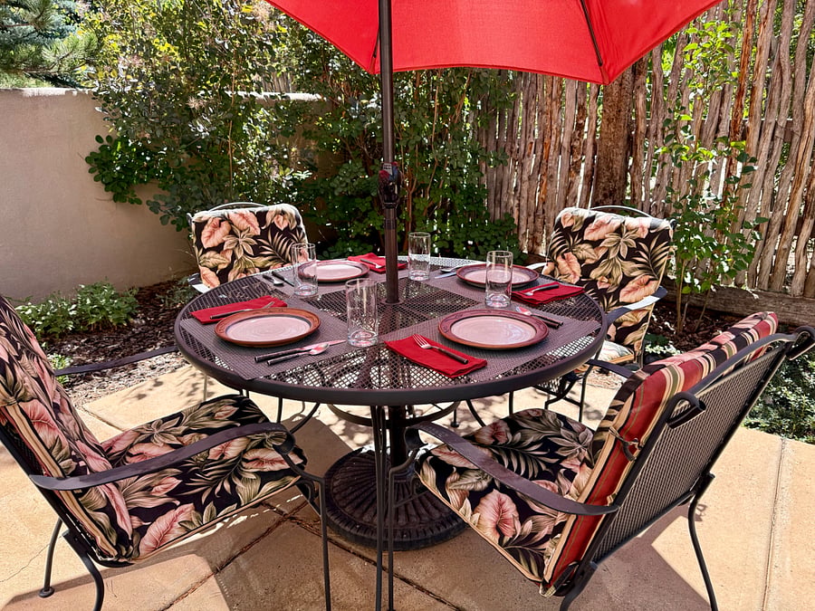 A very private landscaped patio on the south side outside the dining room features a wrought iron table with umbrella.