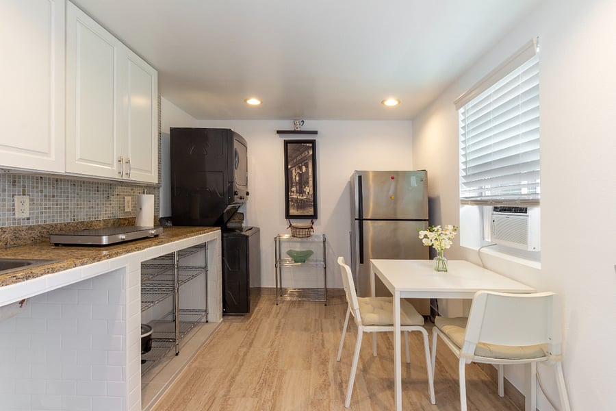 Private kitchenette area with a fridge, cooktop burner, in-unit washer and dryer, and dining table. We provide basic cooking utensils, dinnerware, and cups.