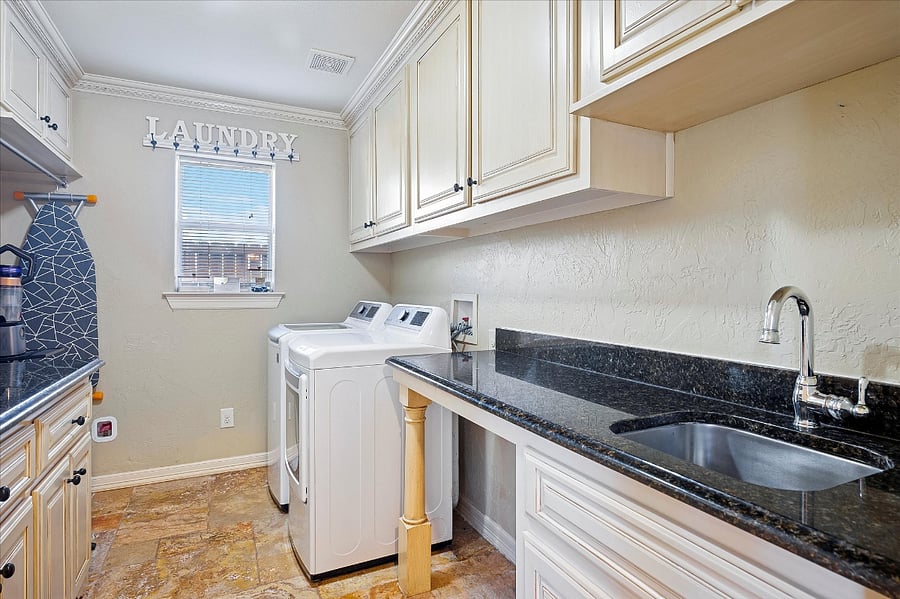 Fully equipped laundry room with a large washer and dryer, iron and ironing board, drying rack, and generous storage and closet space for added convenience during your stay