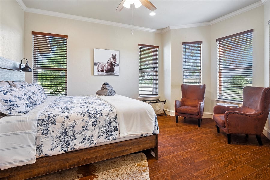 Comfortable main-level second bedroom with a king bed, wall mounted TV, and a detached full bathroom, and peaceful pond views