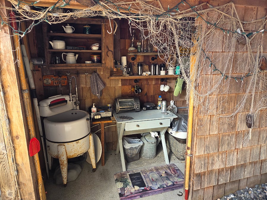 Outdoor kitchen with vintage washing machine made into a sink. There is a hot plate and toaster oven.