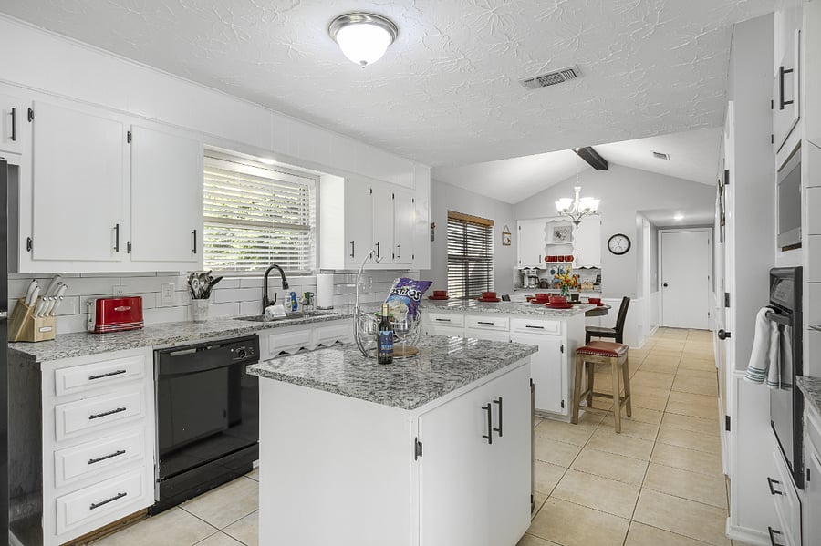 Island/bar seating plus a large open kitchen offers fridge/freezer, dishwasher, many cabinets, and counterspace for prep, microwave, stovetop, and oven.