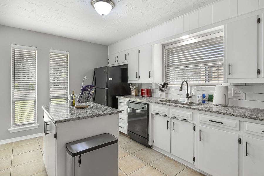 A large open kitchen offers fridge/freezer, dishwasher, many cabinets, large island seating, and counterspace for prep, microwave, stovetop, and oven.
