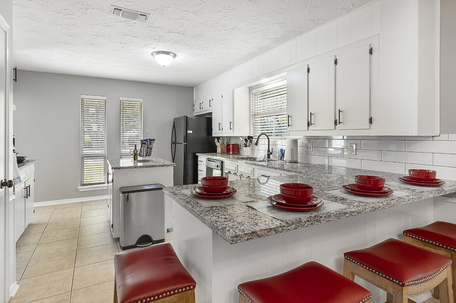 Island/bar seating plus a large open kitchen offers fridge/freezer, dishwasher, many cabinets, and counterspace for prep, microwave, stovetop, and oven.