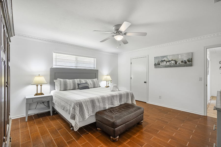 Master bedroom with king bed, TV, ceiling fan, two walk in closets, dresser, wardrobe, and ensuite bathroom.