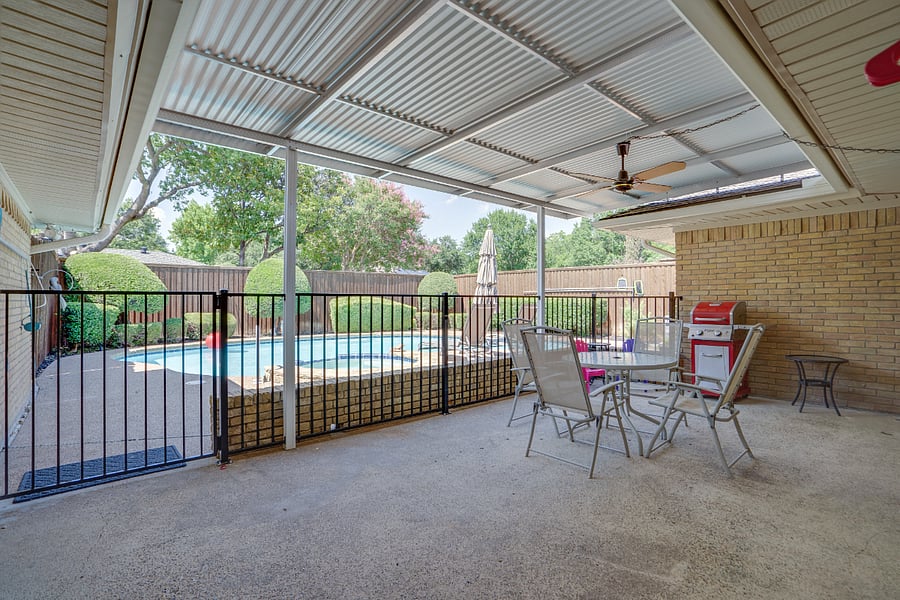 Covered back patio with safety fence to protect kids and pets from unattended pool access.