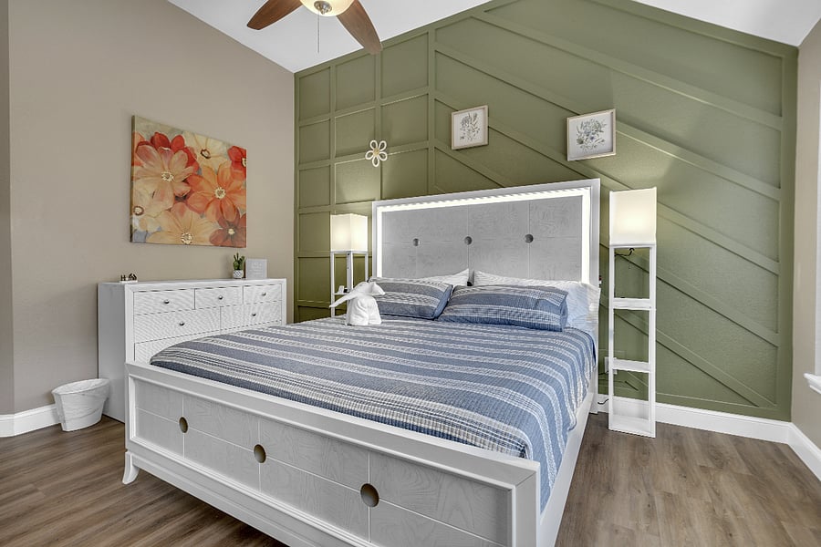 Master bedroom suite with a focus wall, a sitting area, a king bed, a dresser, and nightstands. With an attached, full-custom shower featuring a walk-in shower and a standing tub. Barn Door separates. Smart TV mounted on the wall.