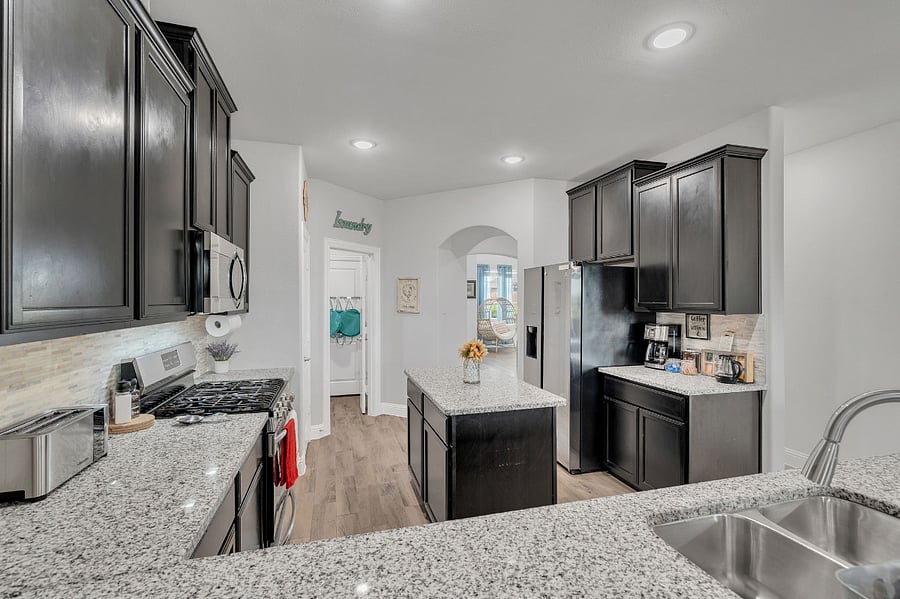Spacious kitchen with abundant cabinetry, granite island prep space, and direct flow into dining and living rooms.