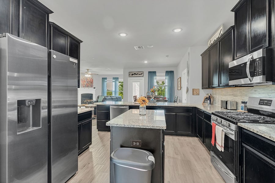Kitchen fully stocked with prep tools, cookware, serving pieces, and place settings for 10. Includes coffee & tea service, refrigerator/freezer, microwave, gas stove & oven, dual sink with disposal, and bar seating that opens to the living room.