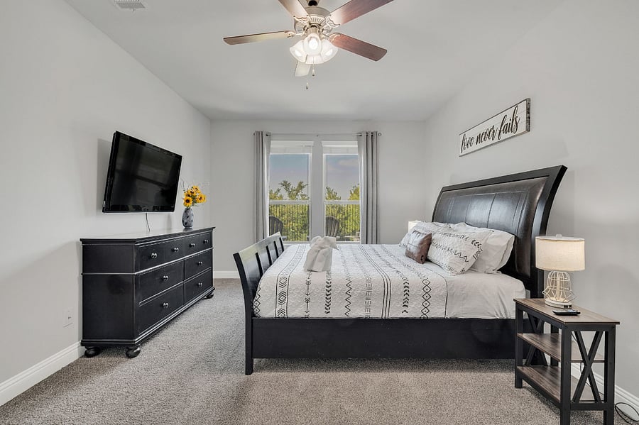 Master bedroom with king bed, desk and chair, dresser, nightstands, lamps, and ceiling fan. Enjoy year-round Lake Lewisville views from the windowsespecially stunning in the fall and winter.