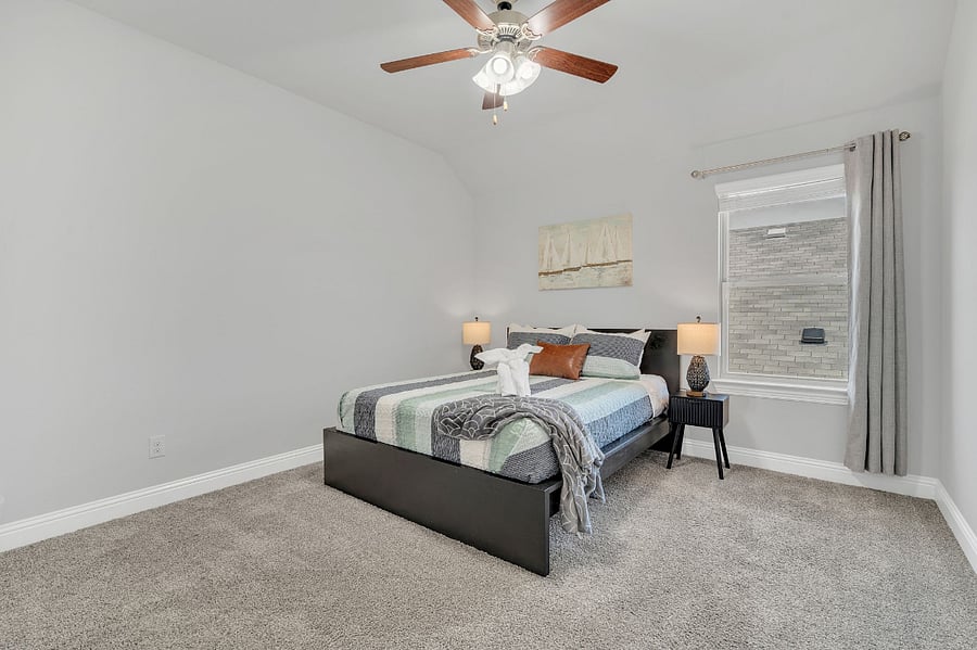 Bedroom with queen bed, nightstands, lamps, and ceiling fan.