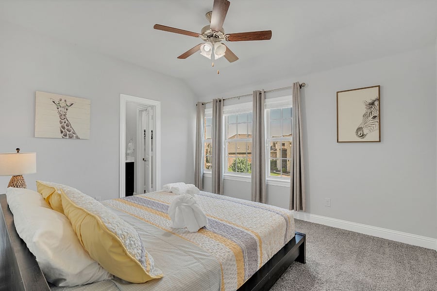 Upstairs bedroom with king bed, ensuite bathroom (tub/shower combo), and walk-in closet (not pictured). Bright natural light and plenty of space for comfort.