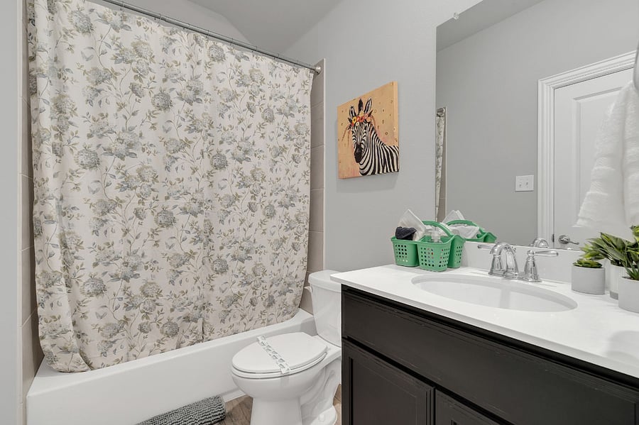 Upstairs bedroom with king bed, ensuite bathroom (tub/shower combo), and walk-in closet (not pictured). Bright natural light and plenty of space for comfort.
